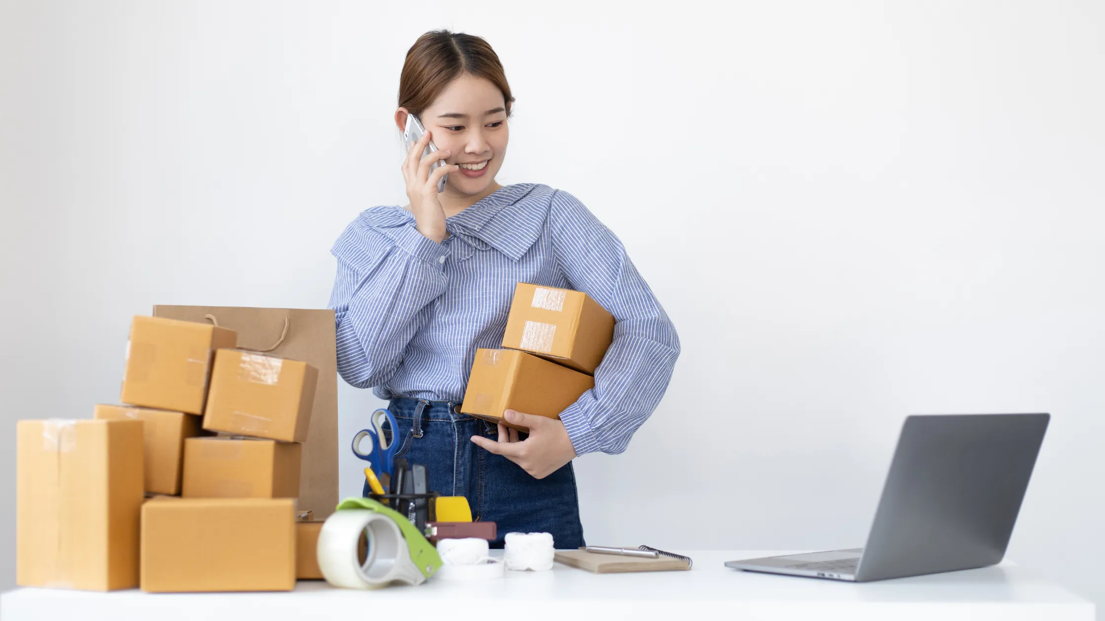電話している女性 段ボールを抱えている