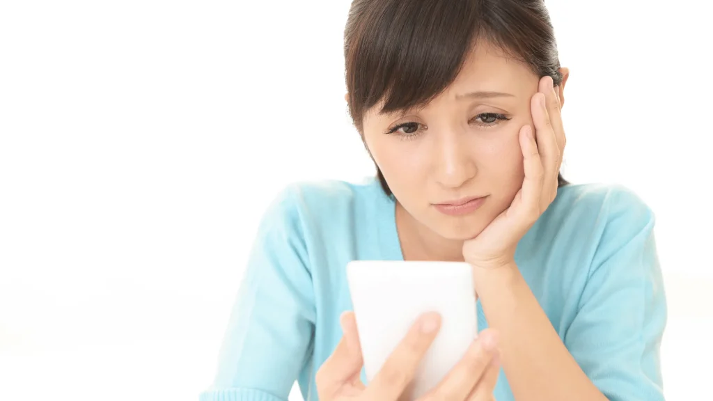 悩んでスマホを見ている女性