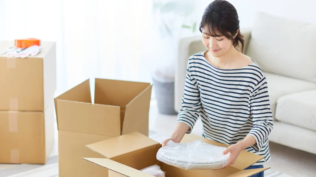 引越しの準備をしている女性、買取アイテムを梱包中